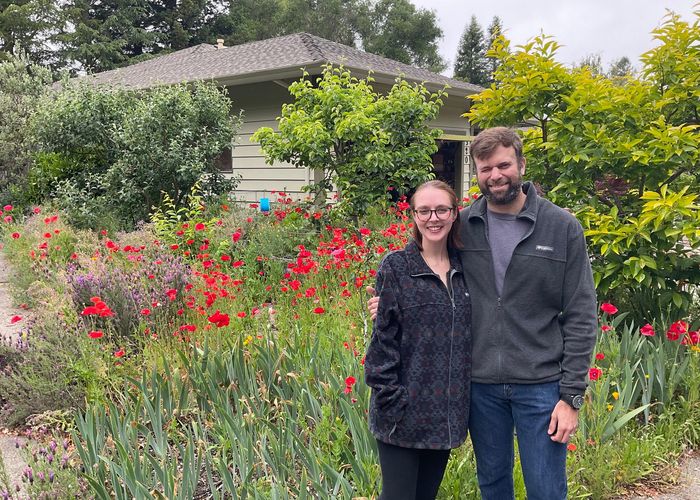 Leila and Dante stand in a garden of red poppies.